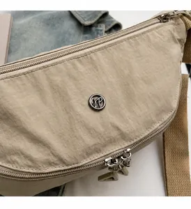 Detalle de bolso beige de nailon con tejido brillante y doble cremallera plateada