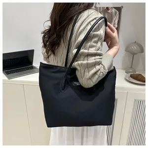 Detailed side view of a large black tote bag worn by a model in a stylish office setting