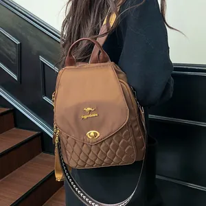 Detail of a brown quilted backpack featuring a golden kangaroo logo and twist-lock closure