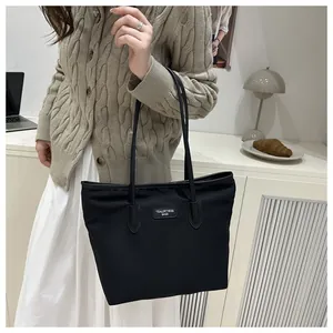 Close-up of a black minimalist tote bag on shoulder with high-quality texture detail