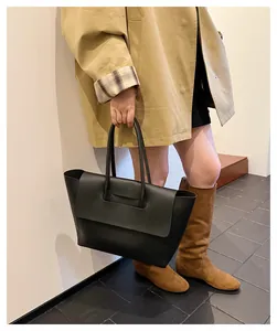Minimalist black leather tote bag shown with khaki trench coat in stylish commute setting