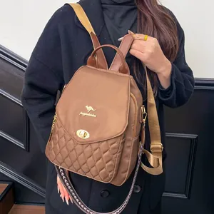 Detail of brown nylon backpack featuring quilted pattern and gold kangaroo metal clasp