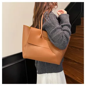 Brown large capacity leather tote bag styled with a grey sweater and white pleated skirt