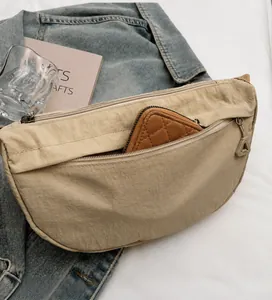 Detalle del bolso de hombro beige que muestra la capacidad del bolsillo frontal con cremallera