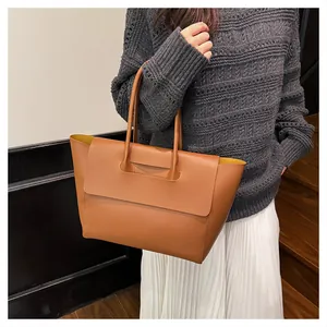 Detail view of caramel leather tote bag styled with a professional autumn outfit