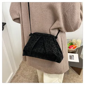 Détail du sac bandoulière noir à motif léopard et texture plissée sur manteau
