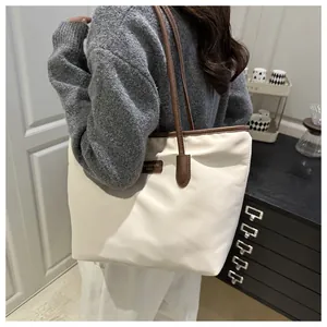 Detail of contrast stitching and leather logo on large cream canvas tote bag