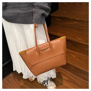Detail view of a large brown leather tote bag with flap closure and contrast yellow lining