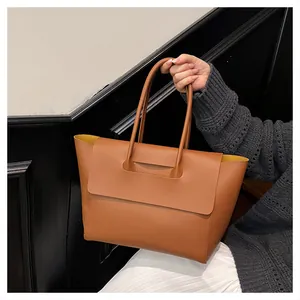Brown leather tote bag featuring a yellow interior lining and minimalist flap closure
