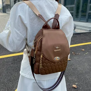 Detail of brown quilted nylon backpack featuring golden metal logo and padlock charm