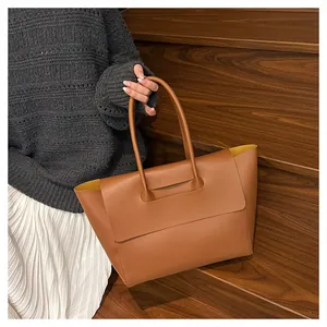 Detailed close-up of brown leather tote bag showing unique yellow contrast interior