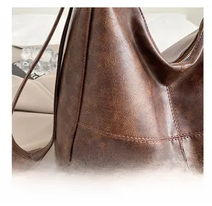 Detail of dark brown hobo bag with vintage textured leather and cross stitching