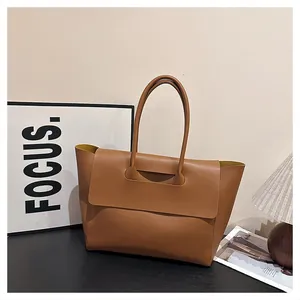 Detail of caramel brown matte leather tote bag with slim handles and yellow lining