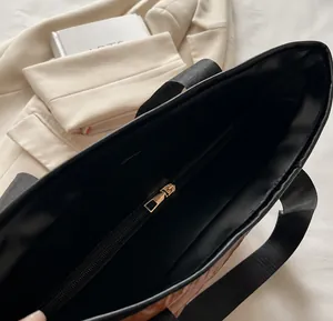 Détail du zip métallique doré lisse et des coutures sur un sac cabas noir chic