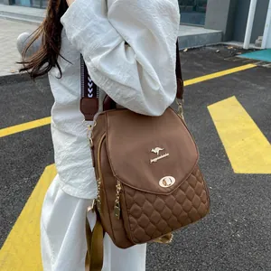 Detail of a brown quilted backpack with a gold logo and adjustable jacquard shoulder strap