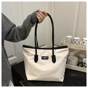 Detail of white canvas tote bag with black leather trim and TidalDryness brand label