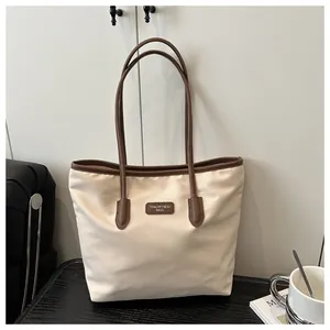 Close-up of the large cream tote bag with brown trim and Tidal Dryness logo detail
