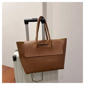 Brown leather tote bag sleeve detail fitting over a silver suitcase handle for travel