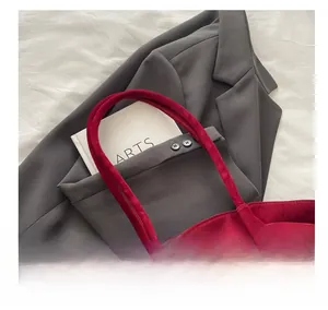 Close-up of wide comfortable handle on a dark red suede tote bag with soft matte finish