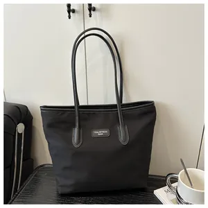 Detailed view of black large capacity tote bag with brand logo on minimalist background