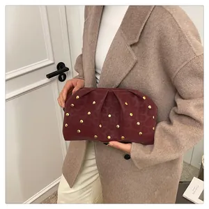 Detail of burgundy ruched clutch bag featuring gold studs and subtle leopard texture