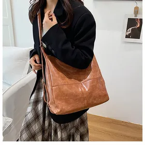 Detail showing the vintage texture and adjustable strap of a brown crossbody tote bag
