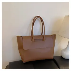 Detailed view of brown leather tote bag with flap closure on a minimalist bench