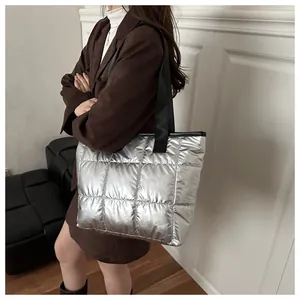 Vista detallada de un bolso tote acolchado plateado con acabado metálico en modelo