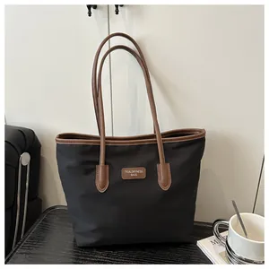 Detail of the high-density black nylon fabric and brown leather handle on a tote bag