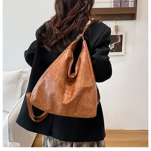 Detail of caramel brown tote bag showing vintage textured faux leather and slim straps