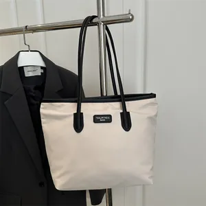 Minimalist cream canvas tote bag with black leather trim and shoulder straps for daily commute