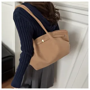 Detail of camel matte tote bag showing long strap and gold square buckle on model