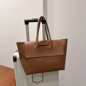 Brown leather tote bag on a silver suitcase handle for stylish office travel commutes