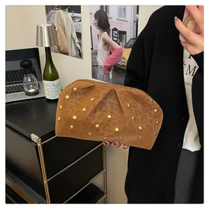 Brown leopard print clutch with gold studs and ruched texture held by a person