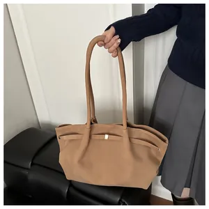 Detailed view of camel suede tote bag with decorative strap buckle held by model