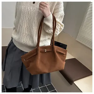Detail view of large brown suede tote bag with minimalist golden metal buckle and long strap