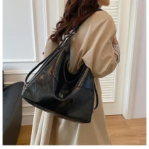 Detail view of black PU leather tote bag with pleated texture on khaki trench coat