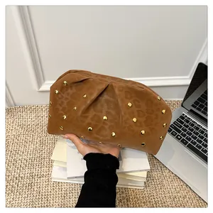 Detail of dark brown leopard print cloud bag featuring gold metal studs and pleated design