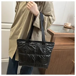 Primer plano del bolso tote acolchado negro con textura de cuadros brillantes y costuras