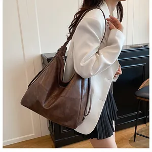 Close-up of a large brown textured faux leather hobo tote bag worn by a model