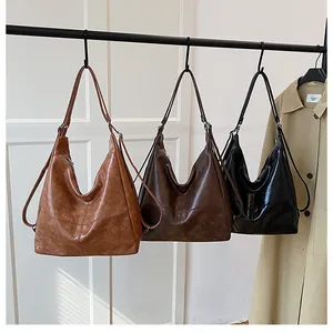 Three-color minimalist faux leather tote bags in brown, coffee and black on a white door