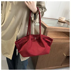 Detail of burgundy matte tote bag with slim handles and metal buckle on female model