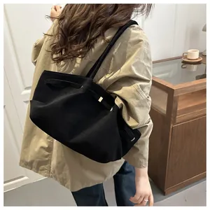 Side view of large black matte tote bag on model's shoulder in a modern interior