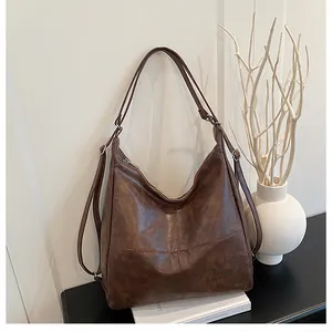 Detailed view of deep brown faux leather tote bag with cross stitching and metal zipper