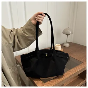 Close-up of a large black vintage tote bag with decorative metal buckle and long handles