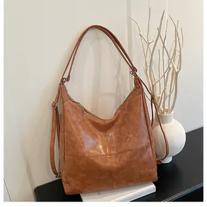 Detail of vintage textured brown PU leather tote with adjustable silver hardware on white book