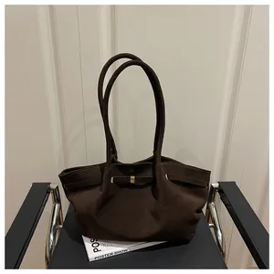 Close-up of deep brown matte tote bag featuring gold buckle detail and long shoulder straps