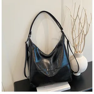 Detail of black oiled leather hobo bag with adjustable silver buckle and glossy texture