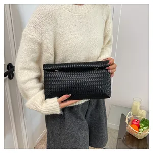 Chic black woven clutch bag with gold metallic clasp detail shown in hand