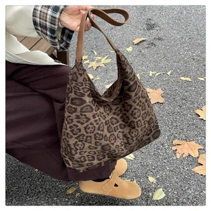 Detail of trendy leopard print tote bag with brown leather strap in autumn setting